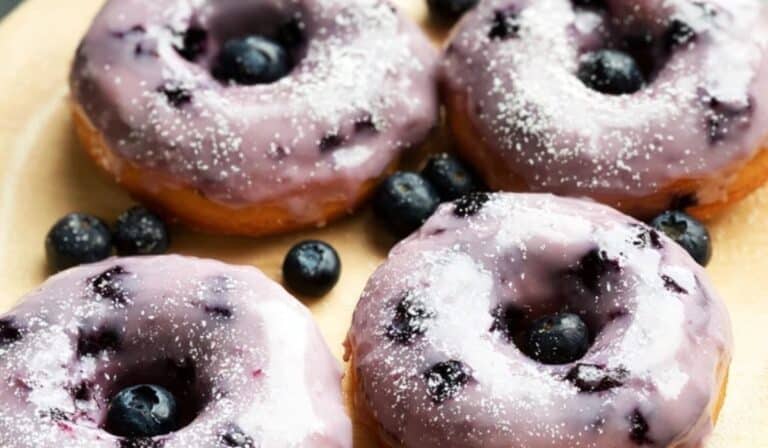 Blueberry Cake Donuts with glaze and powdered sugar on wooden plate