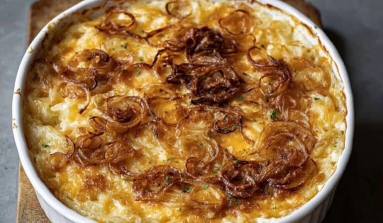 Golden baked French Onion Funeral Potatoes in a round white dish with crispy onion topping