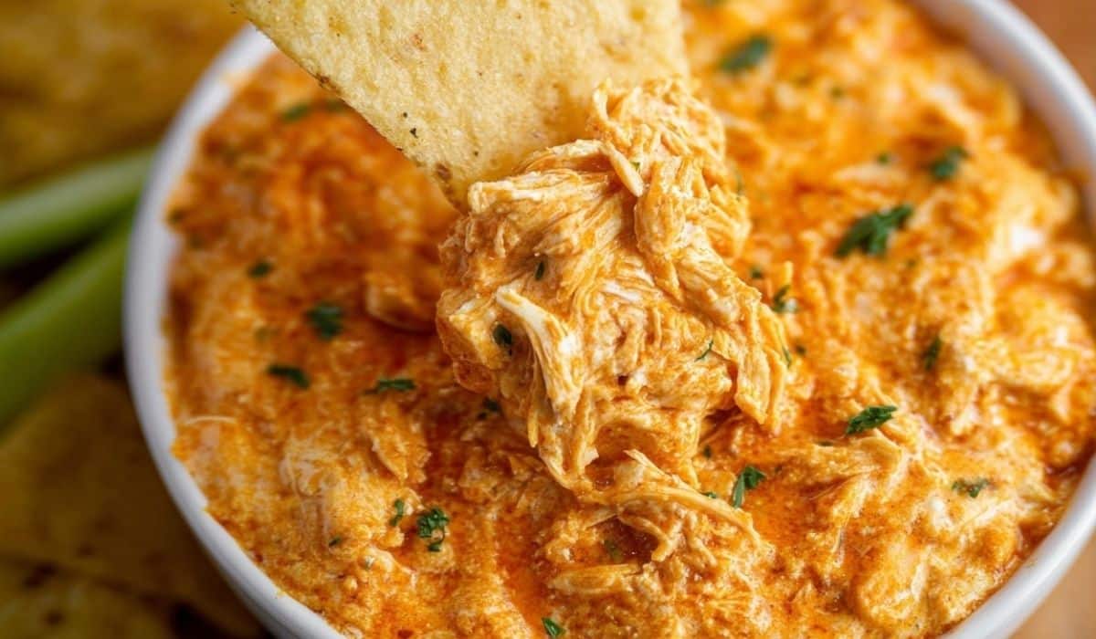 Smoked Buffalo Chicken Dip with tortilla chip being dipped into creamy cheese blend