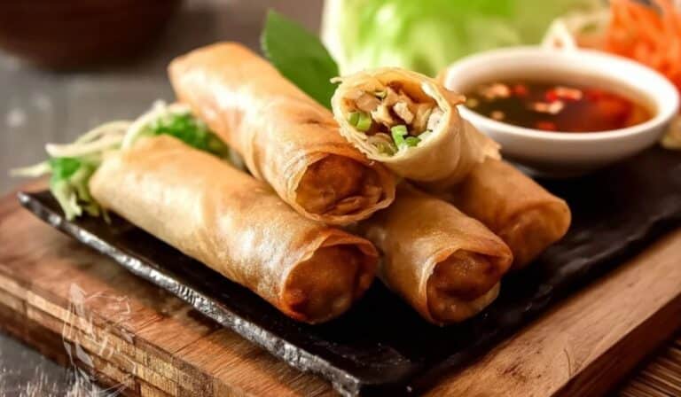 Chicken Spring Rolls served crispy with dipping sauce on a wooden board