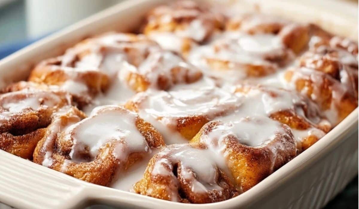 Cinnamon Roll Casserole baked in a white dish with icing drizzled on top