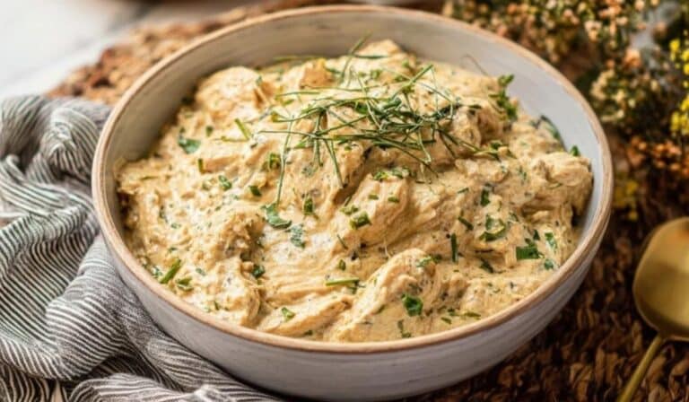 Slow Cooker Cream Cheese Chicken in a white bowl garnished with fresh herbs