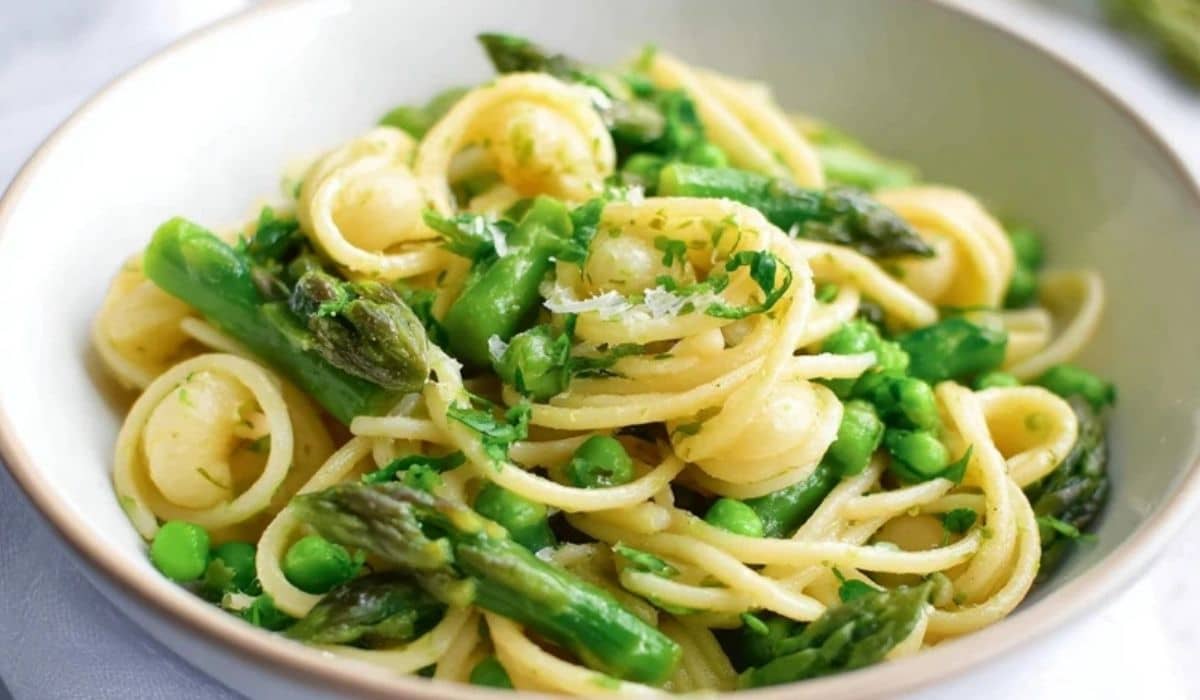 Asparagus Pasta in white bowl with peas and fresh herbs
