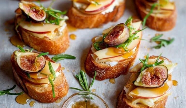 Brie, Apple, and Fig Crostini Appetizer Recipe served with fresh figs and herbs on toasted baguette