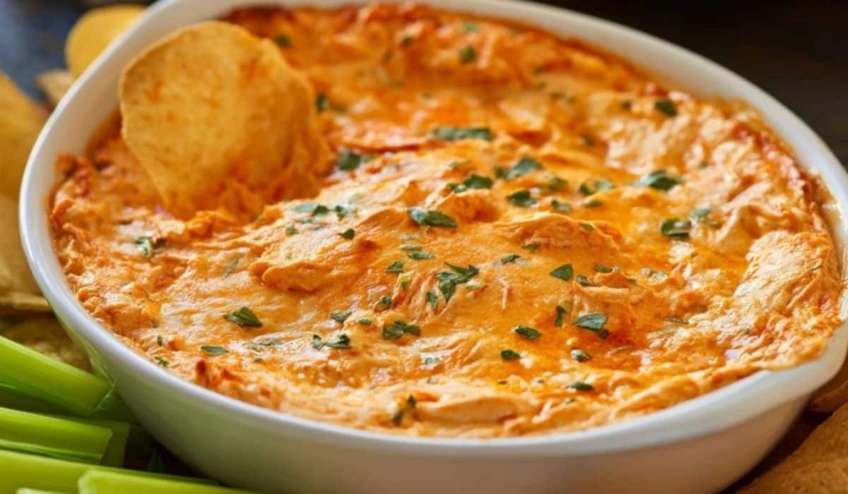 Classic Buffalo Chicken Dip served hot in a white bowl with chips and celery