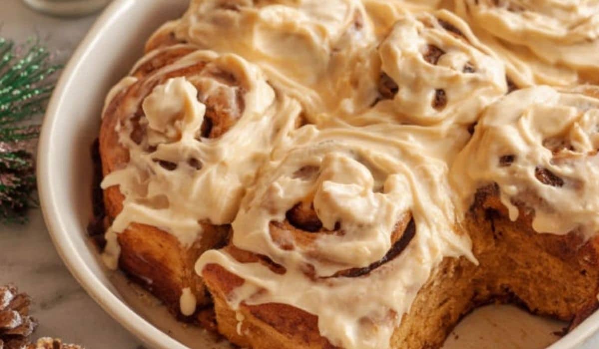 Deliciously Fluffy Gingerbread Cinnamon Rolls in a round white baking dish with cream cheese glaze