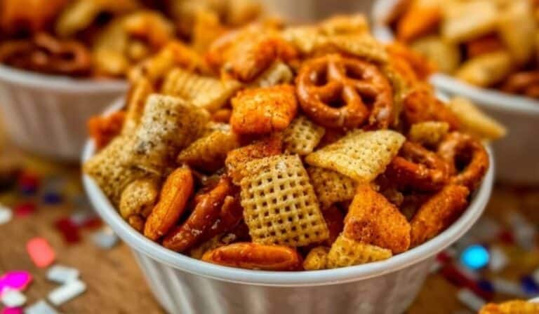 Party Snack Mix in a white bowl with pretzels, Chex cereal, and crackers