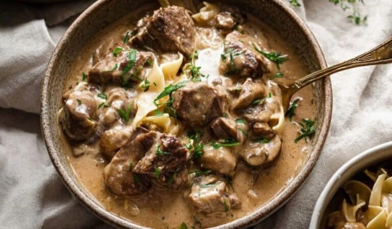 Slow Cooker Beef Stroganoff in a rustic bowl with egg noodles, creamy mushroom sauce, and fresh herbs