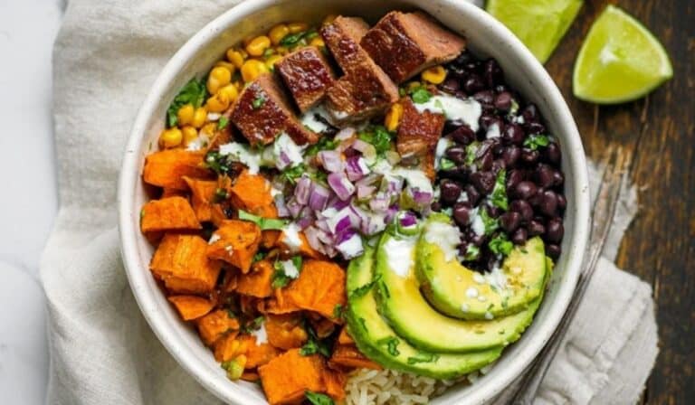 Chipotle steak and sweet potato bowls with avocado and lime on a rustic table.