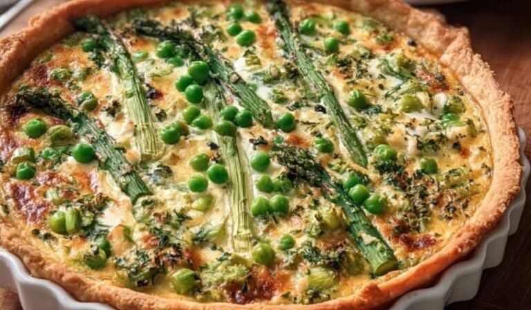 Spring vegetable quiche with asparagus, peas, and leeks in a pie dish with one slice missing